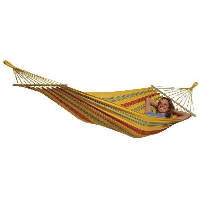 An individual unwinds in an Amazonas Aruba Vanilla Hammock, showcasing lively stripes of yellow, orange, and green. This hammock is weatherproof and features sturdy wooden bars at each end, gently holding the smiling person lying back with their hands beneath their head.