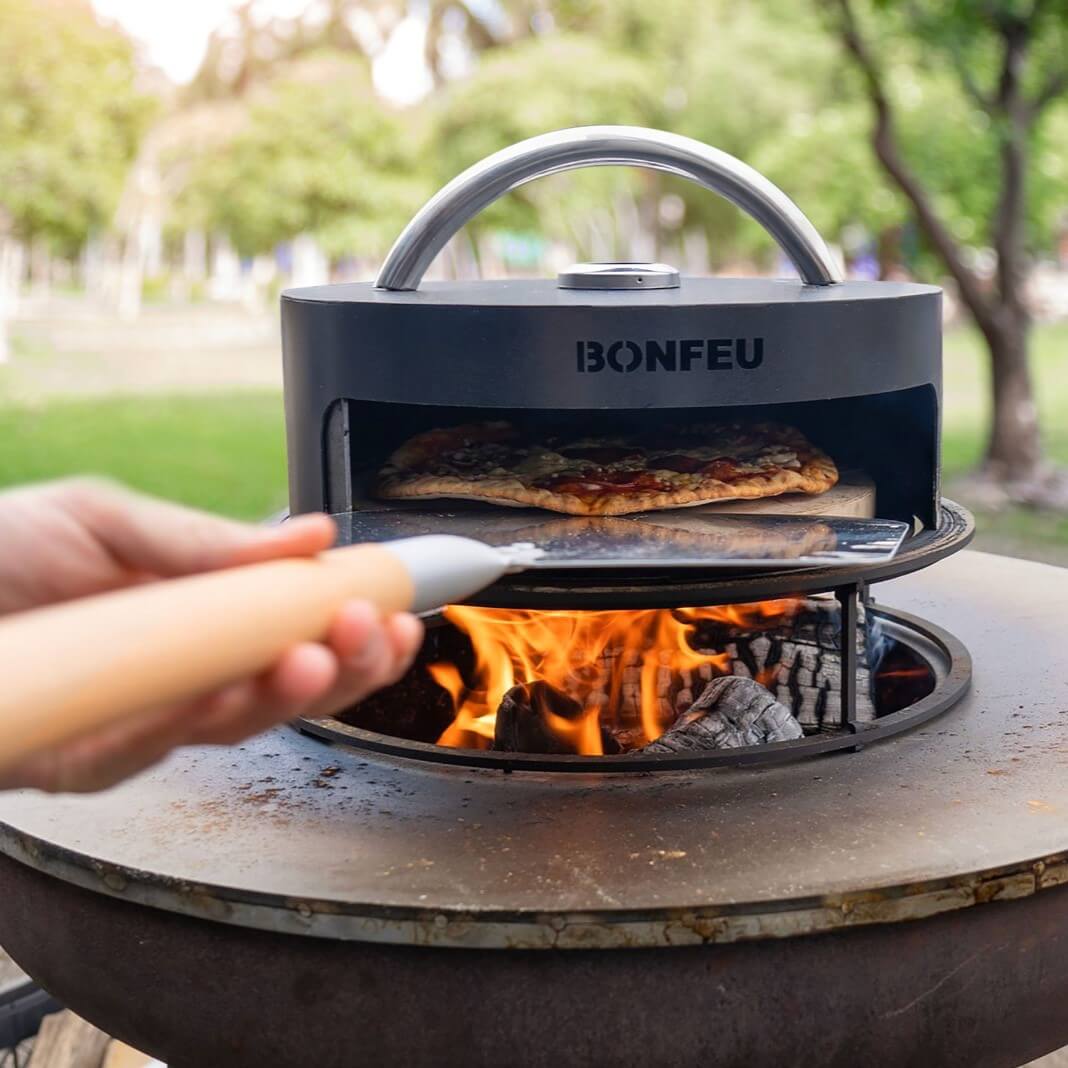 BonFeu BonPizza Oven with Stone-Bonfeu accessories-Bonfeu-BonPizza If there is one outdoor cooking unit that is super popular these days, it is the pizza oven. As it is wood-fired, the BonFeu BonBiza and BonBowl cooking unit lends itself perfectly to making the most delicious pizzas. Let the pizza oven heat up and prepare your pizza in the meantime. You open the oven by lifting or turning the lid until the pizza oven shows an opening. Now you can slide your pizza into the oven with a pizza scoop and watch t