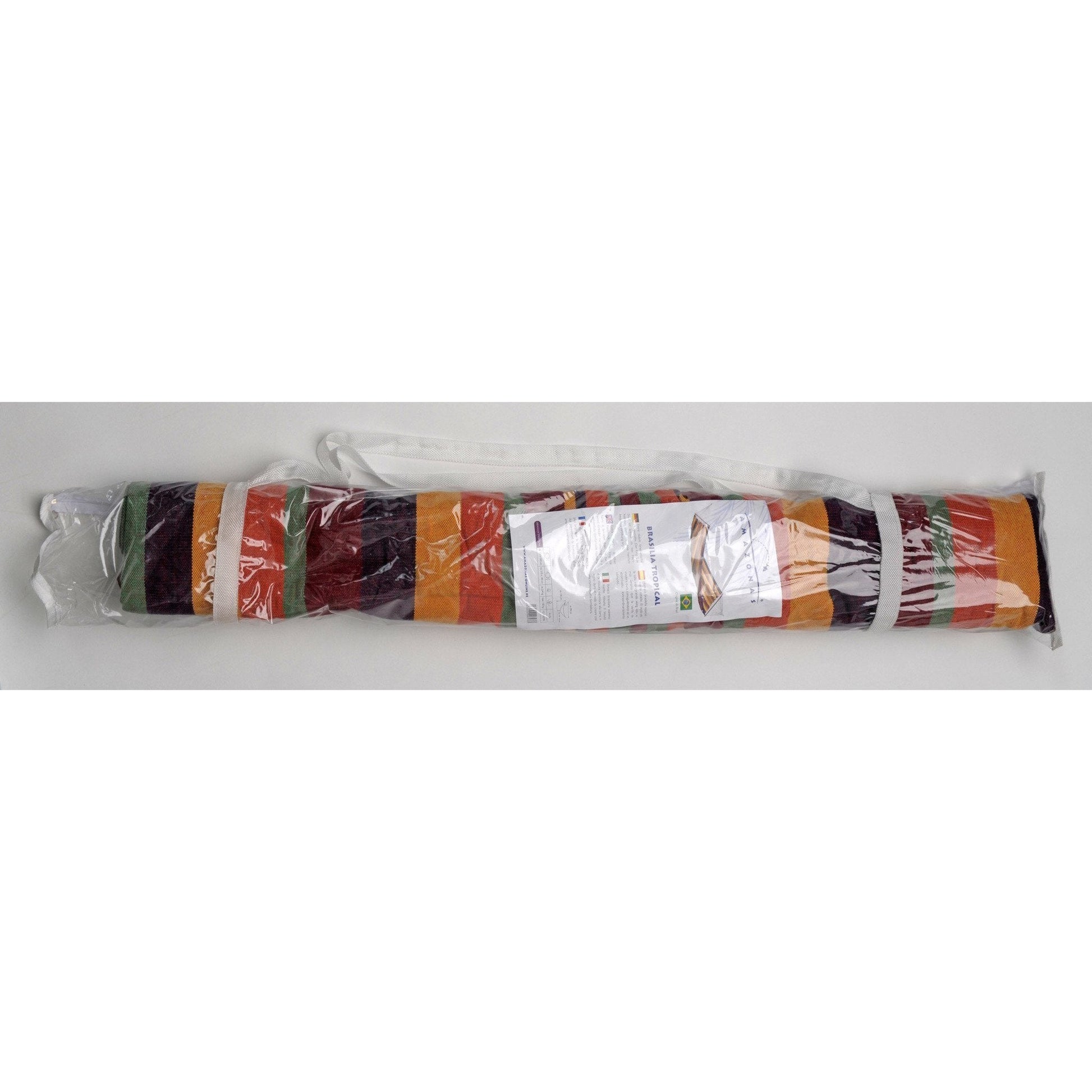 The Brasilia Tropical Hammock by Amazonas, featuring multicolored stripes of orange, green, red, and purple, is made from Brazilian cotton and comes rolled up in a transparent plastic carrying bag. The bag includes a white strap and has attached instructions with images and text.