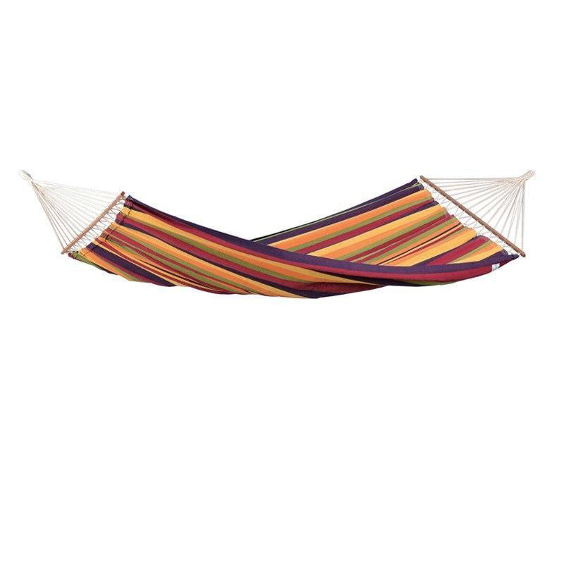 The Brasilia Tropical Hammock by Amazonas is a lively single hammock made from Brazilian cotton, showcasing vibrant stripes in hues of red, orange, yellow, green, and purple. It swings elegantly between trees with its white ropes supported by a graceful spreader bar for ideal relaxation.