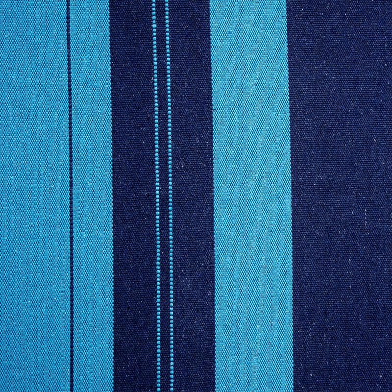 This close-up highlights the Santana Hammock Set by Amazonas, featuring a fabric with alternating vertical stripes of dark and bright blue that showcases the texture and intricate weave pattern typical of Brazilian craftsmanship.