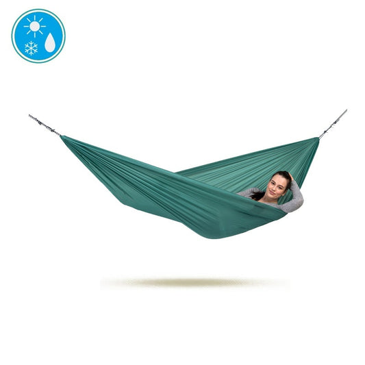 A person is relaxing in the Travel Hammock Set Jungle by Amazonas, effortlessly suspended in mid-air against a white background. An icon in the top left corner displays sun, snowflake, and water symbols, indicating its durability across various weather conditions. The set includes integrated rope and hooks for a secure setup on any adventure.